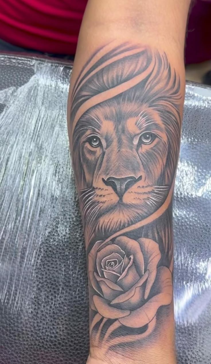 Lion portrait with rose forearm tattoo
