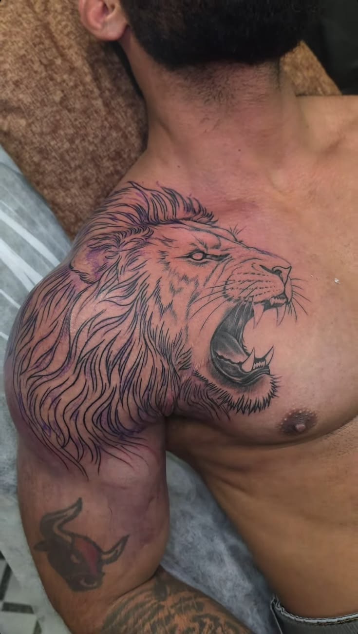 Roaring lion across chest and shoulder tattoo